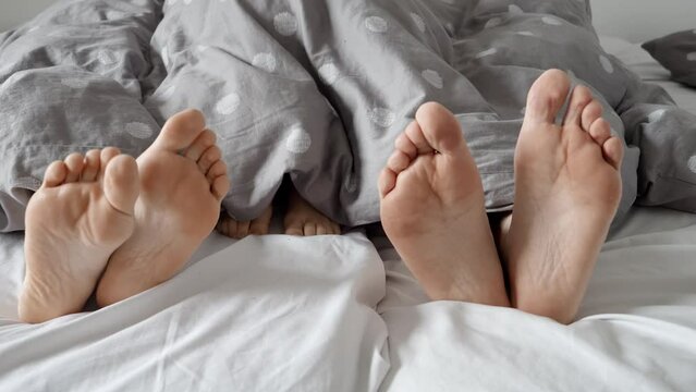 Beautiful and heartwarming stock footage of happy family's feet lying together under the blanket. Feeling of warmth, security, and love