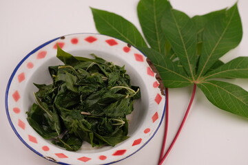 daun singkong rebus. boiled cassava leaves on vintage plate. useful for preventing anemia, digestion, a source of energy, metabolism. healthy food, suitable for vegans and vegetarians. gulai. curry. 