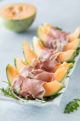 A row of cantaloupe spears wrapped in prosciutto, ready for snacking.