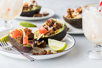 Avocado boats filled with guacamole and topped with taco fixings.