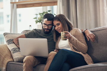 You can find so much more at the online store. a young couple using a laptop and credit card on the sofa at home.