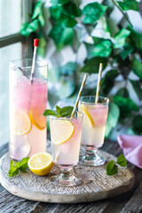 Frosty glasses of cold lemonade with pink lemonade ice cubes.