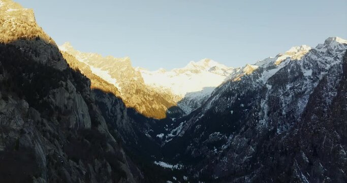 Aerial Pan Down Shot From Snow Covered Landscape Down To Val Di Mello Valley Forest. Establishing Shot