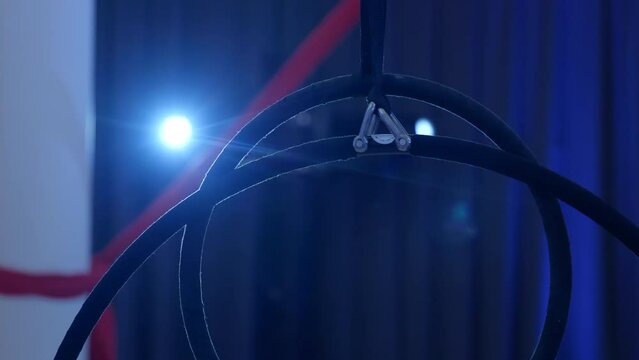 Close up of acrobatic rings at indoor stage with blue backlight, panning