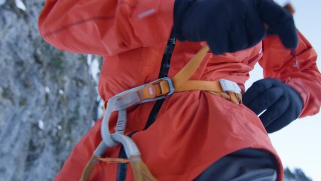 An athlete puts on and tightens his harness to climb an ice fall, in the Alps, Switzerland