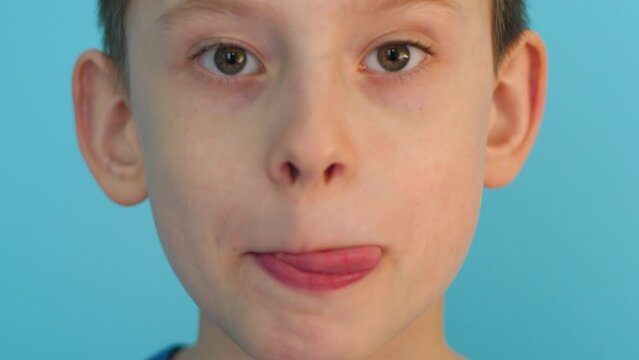 portrait of a hungry caucasian cute boy licking his lips looking at the camera. selective focus. appetizing food concept, drooling from hunger