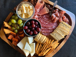 Tray of appetizers, cold cuts, cheeses, olives,crackers,almonds,grapes, salami,  crackers, prosciutto etc. from above Generative AI