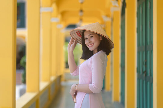 A pretty Vietnamese young Asian woman wearing an Ao Dai a traditional Vietnam dress national costume color pink Ao Dai is popular in Hoi An Old Town, Quang Nam, Vietnam.