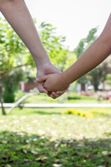 Dos personas tomadas de la mano, madre e hija, ellas están en un parque, día soleado