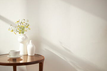 Vases and objects on the table in a warm room with sunlight coming in