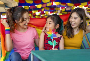 young asian lesbian couple take care of kid as a daughter, they are having fun together outdoor on beach chair while travelling on summer, concept of LGBT lifestyle, cohabitation, diversity family lov