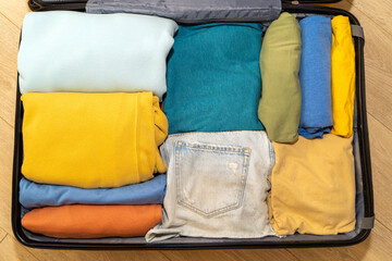 Top down view of an open suitcase filled with travel clothes. The concept of summer holidays,...