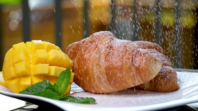 french breakfast in spring outside sprinkle croissant with powdered sugar like snow mango leaf mines hotel vacation trip travel agency place for text grains of sugar on white plate on balcony France