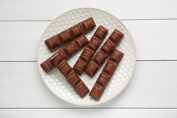 Tasty chocolate bars on white wooden table, top view