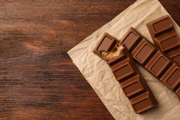 Tasty chocolate bars on wooden table, top view. Space for text