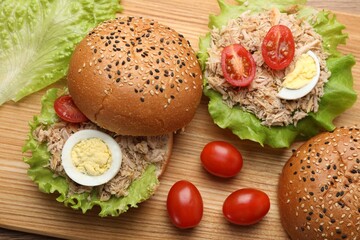Delicious sandwiches with tuna, boiled egg and vegetables on wooden board, above view