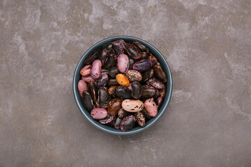 Bowl with dry kidney beans on grey table, top view