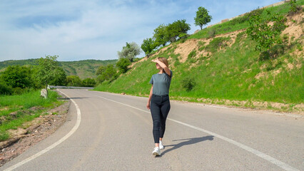 Young woman traveller walk in mountain road in western Tien Shan, Uzbekistan.