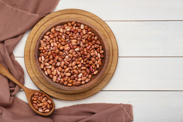 Bowl and spoon with dry kidney beans on white wooden table, flat lay. Space for text