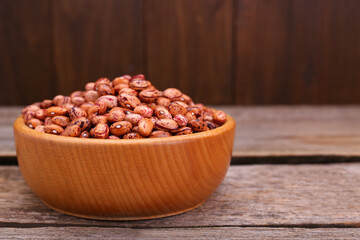Bowl with dry kidney beans on old wooden table, closeup. Space for text
