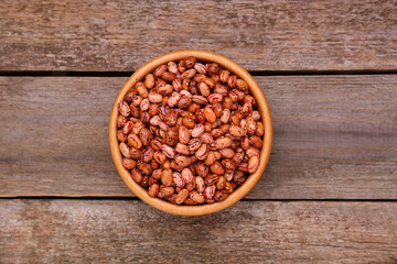 Bowl with dry kidney beans on old wooden table, top view