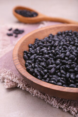 Bowl of raw black beans on light grey table, closeup