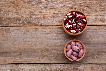 Different kinds of dry kidney beans on wooden table, flat lay. Space for text