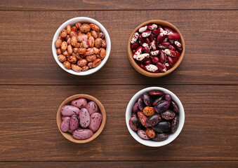 Different kinds of dry kidney beans on wooden table, flat lay