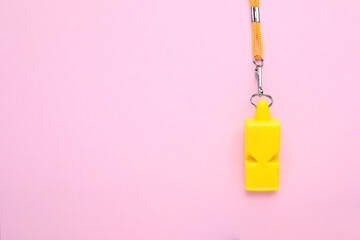 One yellow whistle with orange cord on pink background, top view. Space for text