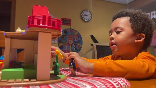 3-year-old sweet black child plays with his toy house at home.
