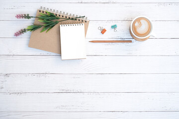 Mockup, Blank notepad and coffee cup with green plant on wooden white table desk background ,Top view with copy space, Flat lay  