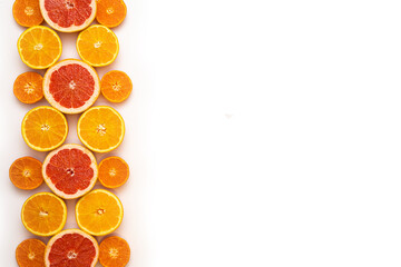 Fresh sliced and halved citrus fruits as a pattern in the left third of the image on a white background.