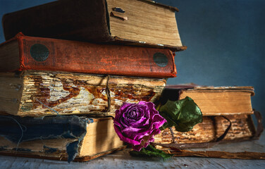 Still life with a stack of old books and a dried rose.
