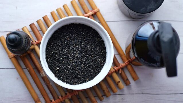 Black Cumin seeds and oil in a container on table 