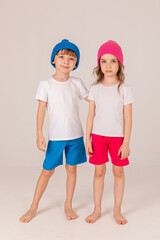 Happy, funny, little girl and boy, brother and sister in a blue and pink clothes on white background. Pink and blue knitted hats on the heads of children. Kids, children having fun on ski resort