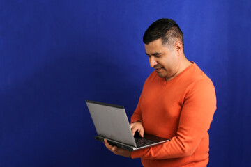 Dark-haired latino adult man uses laptop for work, online shopping, dating in apps looks excited and points finger