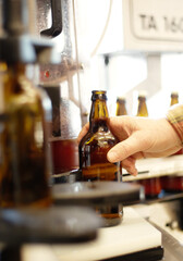 Hands, beer and bottle in factory, brewery or manufacturing plant for quality inspection. Alcohol, production line and person taking glass from automatic conveyor machine with product in warehouse.