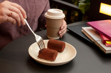 woman eating cakes and drinking coffee in cafe at black table