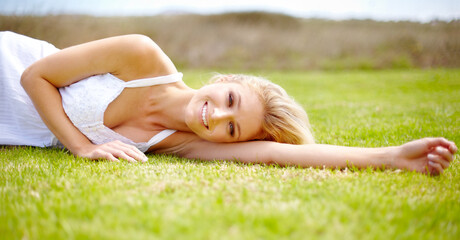 Portrait, rest and a woman lying on grass outdoor in nature during summer for peace or quiet on a field. Spring, garden and relax with a young person relaxing outside on green ground in a countryside