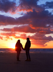 Couple, silhouette and sunset sky at the beach on a romantic date, vacation or holiday in nature. Man and woman holding hands with love and care on travel, adventure or trip with clouds and ocean