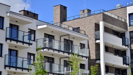 Obraz premium Modern apartment buildings on a sunny day with a blue sky. Facade of a modern apartment building. Contemporary residential building exterior in the daylight. 