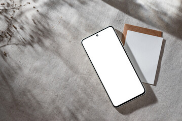 Mobile phone with empty screen mock up on neutral beige linen background with aesthetic floral sun...