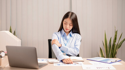 Businesswoman asia is sitting at workplace and feeling muscle aches from hard work.