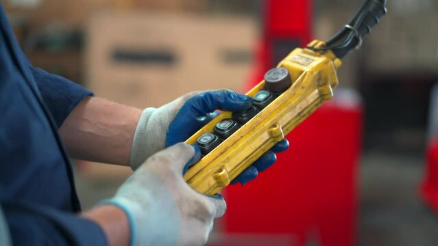 Factory worker - technician controlling a heavy crane in factory close up at his hands holing a crane controller.