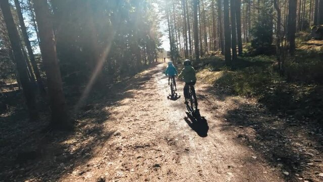 boy and girl cycling in the forest together on a beautiful day