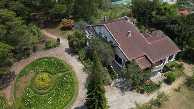 Aerial footage above old french colonial house in Dalat city, Vietnam. Camera is rotating from right to left showing the architecture and the nearby surrounding with a nice park