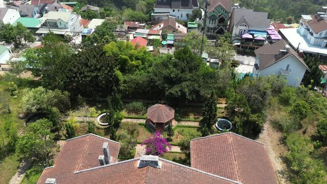 Aerial drone footage above old french colonial house in Dalat city, Vietnam. Camera is moving backward