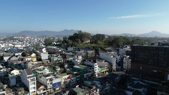 Aerial footage above Dalat city center in south Vietnam. Camera is moving foward above the roof of houses and stop in front of a small french colonial mansion on a hill