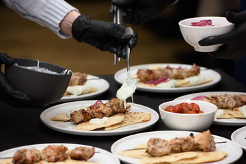 the chef in the restaurant prepares souvlaki with pita and tzatziki sauce