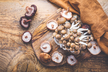 Raw brown shimeji mushrooms and shiitake on cutting board